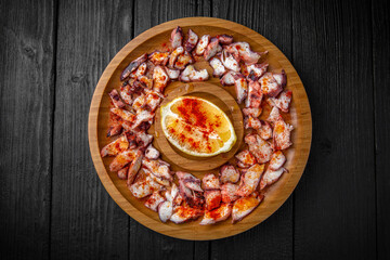 Thinly sliced lard and bacon with chili, paprika and lemon. Snack for Oktoberfest beer or vodka. Wooden plate on black boards.
