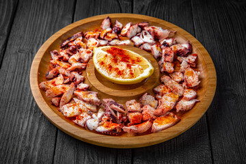 Thinly sliced lard and bacon with chili, paprika and lemon. Snack for Oktoberfest beer or vodka. Wooden plate on black boards.