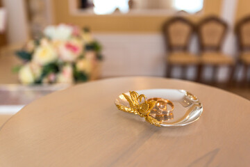 Two gold wedding rings on a ring stand in the wedding palace before the ceremony. Close-up