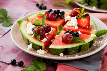 Fresh summer salad with berries and fruits on watermelon with feta cheese
