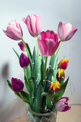 A bouquet of beautiful fresh blooming tulips wrapped in a thin silver wire with LEDs on a white background