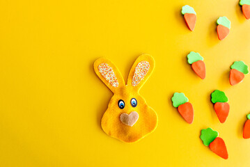 Easter decoration, easter bunny and carrots on yellow background.