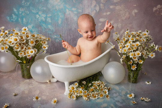 A happy laughing child takes a bath, splashes and has fun. A small child in the bathtub. Smiling baby in the bathroom