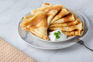 Stack of russian thin pancakes blini with fresh sour cream