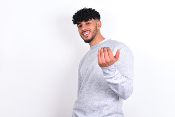 young arab man with curly hair wearing sport sweatshirt
over white background inviting to come with hand. Happy that you came - obrazy, fototapety, plakaty