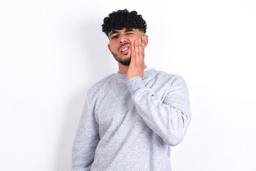 young arab man with curly hair wearing sport sweatshirt
over white background touching mouth with...