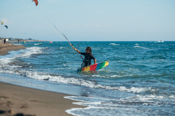 Woman holding kiteboard and going into the water