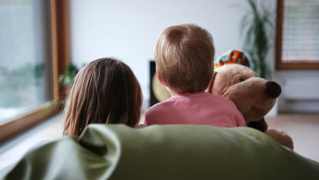 Two Caucasian Loving Sisters Children Girls Spending Time Together Watching Cartoon on TV in Living Room