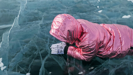Girl walking on cracked ice of frozen lake Baikal. Woman traveler explores and looks at an ice...