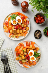 Sweet potato gnocchi with teriyaki tofu with indonesian vegetable salad gado gado - carrots, cucumbers, tomatoes, coriander, sesame seeds, boiled eggs and peanut butter dressing on a white plate