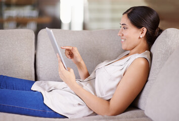 Surfing with the touch of her finger. Shot of a young woman lying on a sofa using a digital tablet.