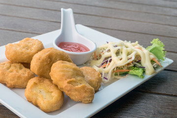 Close up of delicious crispy fried chicken nuggets with sauce and salad