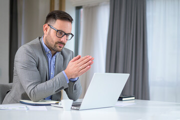 Serious businessman entrepreneur in office making important online video conference call, explaining discussing about serious problem opposing confronting other meeting participants