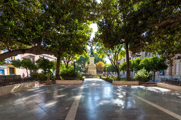 Naklejka premium The shaded urban Plaza del Museo a Seville across from the Museum of Fine Arts in Seville, Spain with the monument to Bartolome Esteban Murillo the sculptor.
