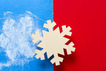 wooden snowflake ornament on red and blue paper with chalky residue 