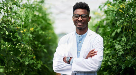 Plants are living organisms that need caring like us all. Portrait of a handsome young botanist posing with his arms folded outdoors in nature.