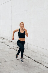  Young woman in black sportswear running through the city. vertical photo for social networks