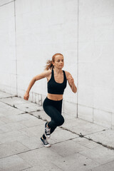 Attractive beautiful woman wearing sportswear running at urban spot. Fit woman jogging outdoor. Healthy and active lifestyle concept.
