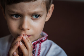Fototapeta premium A little boy prays to God with his hands tucked open with his eyes open.