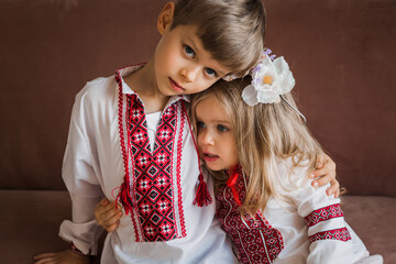Brother and sister in ukrainian dresses, sitting on sofa.