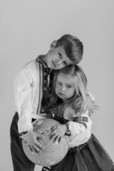 A closeup  black and white portrait ukrainian boy and girl holding an earth globe map in his hands, looking to the camera