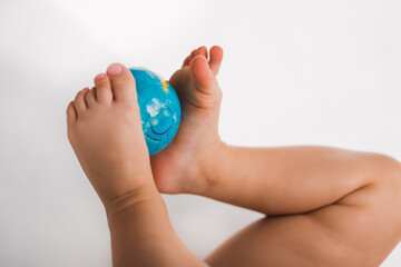 close up  earth globe map holding by baby legs on white background