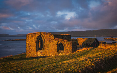 The ruins of St. Magnus Cathedral in Kirkjubour Kirkebo a historical village on Streymoy, Faroe Islands. The ruins are the largest medieval building in the Faroe Islands. Sunrise time, november 2021