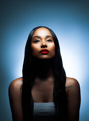 Fototapeta premium Self-acceptance breeds confidence. Shot of an attractive young woman posing against a blue background in the studio.