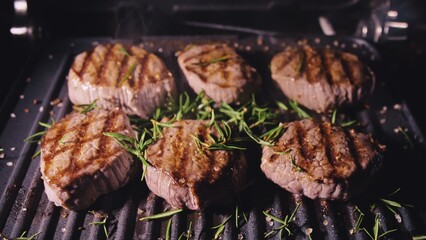 Delicious juicy meat steak cooking on grill. Aged prime rare roast grilling tenderloin fresh marble tenderness beef. Prime beef fry on electric roaster, rosemary, black pepper, salt. Slow motion.