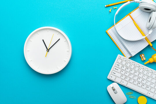 Flat lay image of office and deadline concepts over turquoise blue background. View from above on the office table with watch as working day concept. Top-down composition of time management concept.