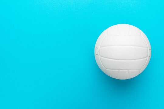 Top view photo of white volleyball ball as football concept . Minimalist flat lay image of leather volleyball ball over blue turquoise background with copy space and right side composition.