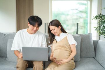 パソコンを見る妊婦と男性（笑顔）
