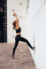Young Parkour and Freerunning women doing a backflip from a wall in an urban background, jumping tumbling Gymnastics training concept
