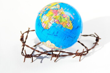 Our planet is in danger  Earth globe over defocused and rusty barbed wire on white background.   