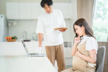 Obraz premium パソコンを見て考える妊婦と男性 