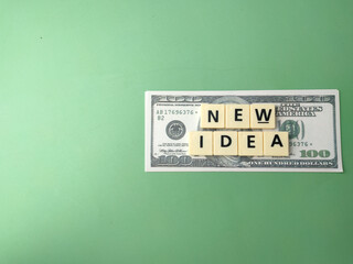 Top view toys word and banknotes with text NEW IDEA on green background.