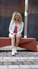 Beautiful businesswoman sitting on a bench and holding her phone in her hand