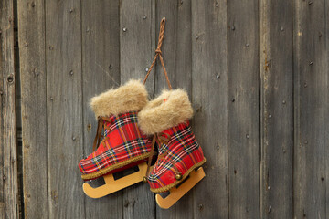 Ornamental fur lined plaid skates hanging from a wood plank wall