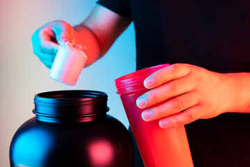 Man with measuring whey protein scoop and jar, preparing protein shake - Gym