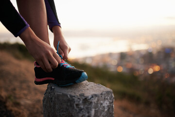 Feeling good and keeping fit. Cropped shot of a runner tying her shoelaces.