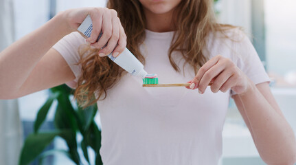 Dont forget to brush your teeth twice a day. Shot of a young woman applying toothpaste to a toothbrush.