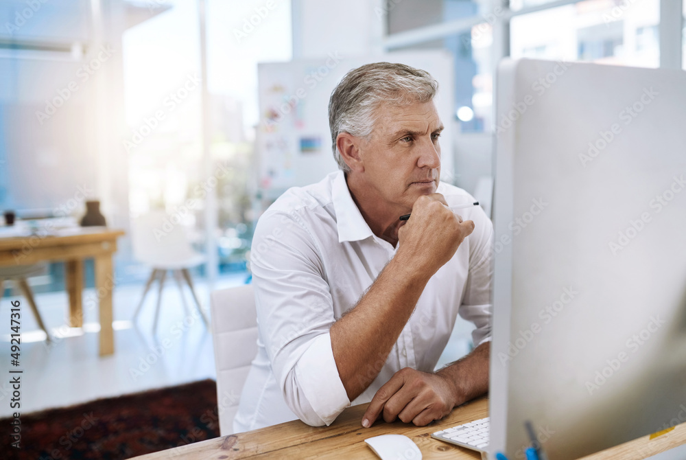 Poster I wonder if I should change it. Shot of a mature businessman working on his computer while sitting in the office at work.