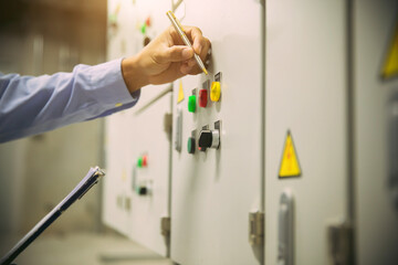 Electricity and HVAC AC system service, Technician checking air handling unit AHU starter button control panel of heating and air conditioning or air conditioner load center cabinet for maintenance.