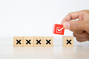 Hand choose check mark on cube wooden toy block stack with cross symbol for true or false changing...