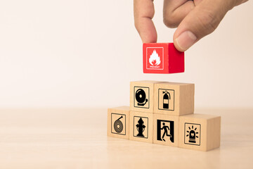 Hand choose cube wooden block stack with fire icon and door exit sing or fire escape with prevent icon and fire extinguisher and emergency prevention or protection symbol for safety and rescue. - obrazy, fototapety, plakaty