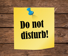 Do not disturb yellow paper office note with a red thumb tack as a warning sign to be quiet and not noisy to allow for relaxation and silence in a peaceful healthy environment with no sound pollution.
