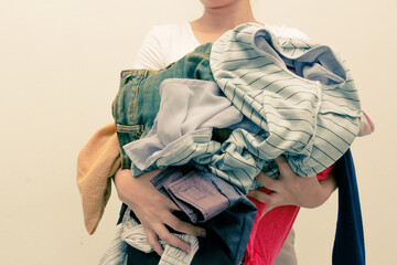 Woman holding a huge pile of clothes . Laundry, Clothing