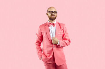 Portrait of young Caucasian man in suit and glasses isolated on pink studio background. Male performer and entertainer in fancy costume look at camera. Entertainment and party concept.