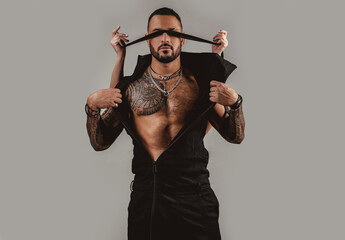 Brutal man with ribbon on eyes, serious handsome guy. Trust concept. Muscular macho man with...