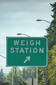 weigh station sign near green forest and road
